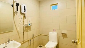 A small, clean bathroom with a toilet, sink, and shower. - Luna Guesthouse (Semporna)