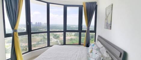 A bedroom with a large window, a bed, and a painting on the wall.