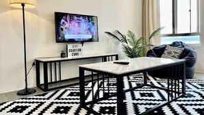 Ein modernes Wohnzimmer mit Fernseher, einer Konsolentisch, einem gemusterten Teppich und einem Fenster mit Blick.