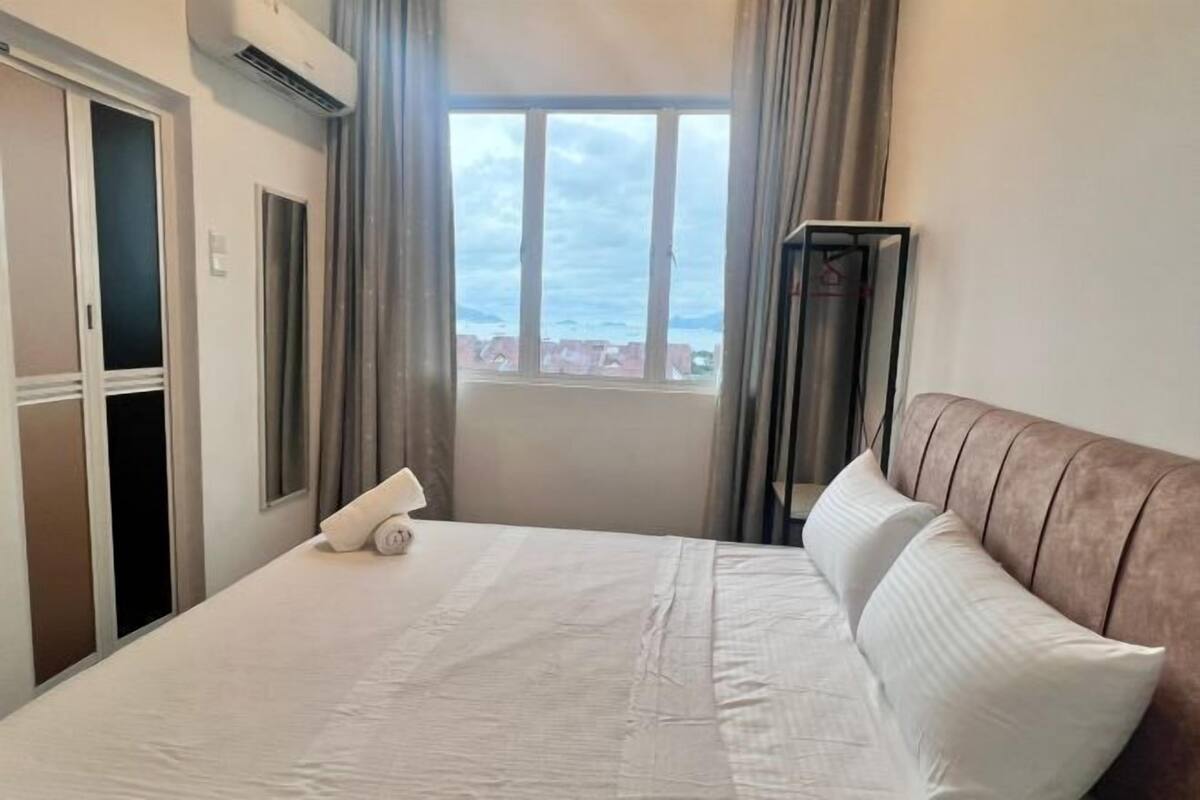Habitació d'hotel amb un llit, una finestra amb cortines, un armari i un aire condicionat.