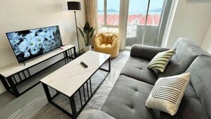 Ein modernes Wohnzimmer mit Sofa, Couchtisch, Fernseher und einem großen Fenster mit Blick.