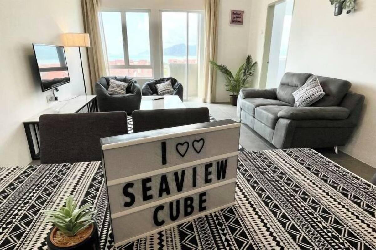 Un saló modern amb un sofà, una taula de centre, una televisió i un cartell que diu 'I ♥ SEAVIEW CUBE'.