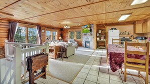 A cabin interior with a living area, kitchen, and a stone fireplace.