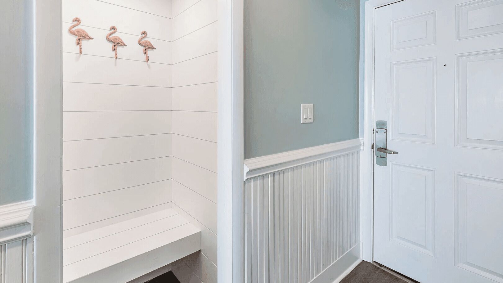 A bathroom with white tiled walls, a white door, and a light blue accent wall.