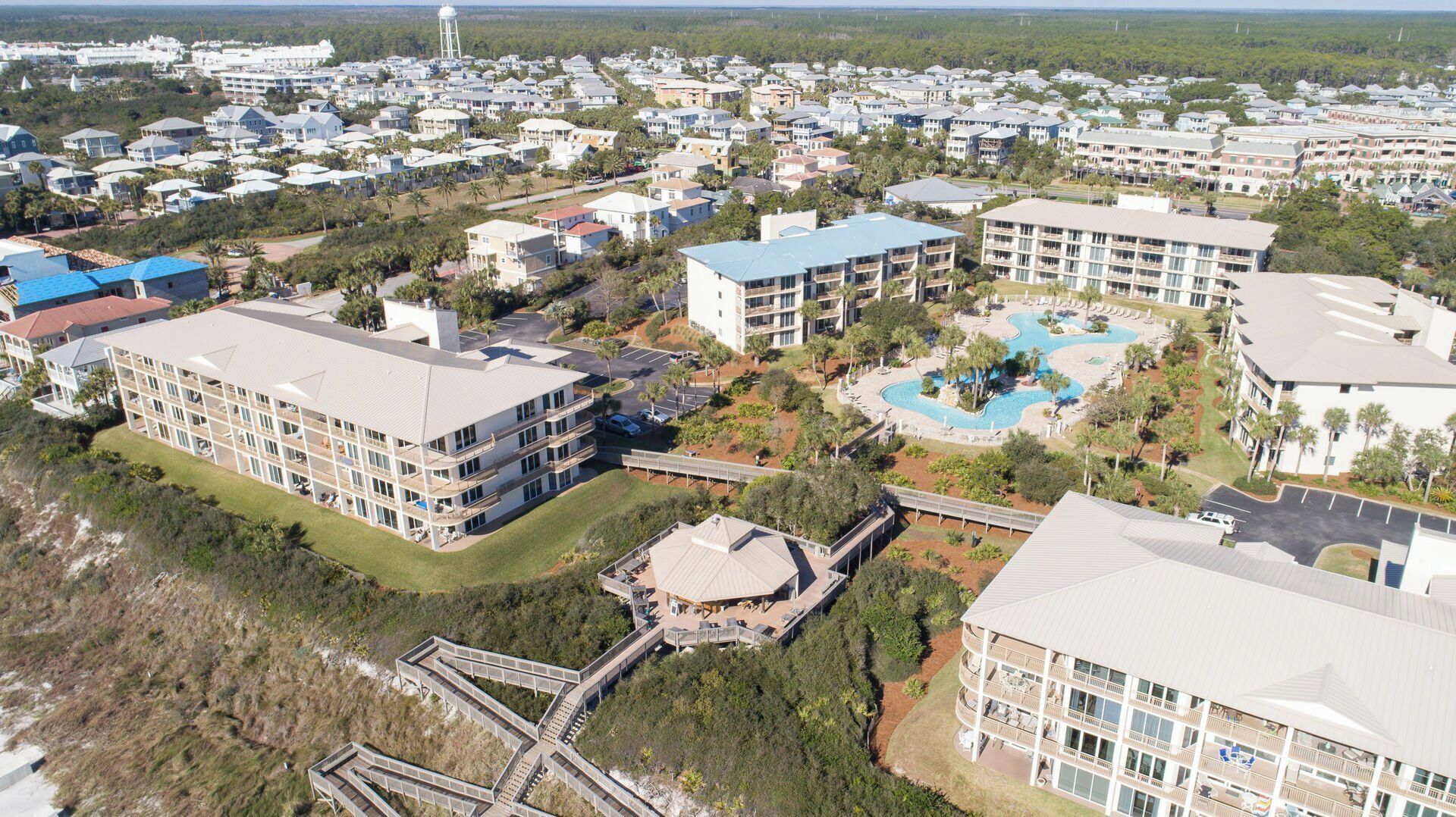 An aerial view of a resort with multiple buildings, a swimming pool, and a bridge connecting different areas.