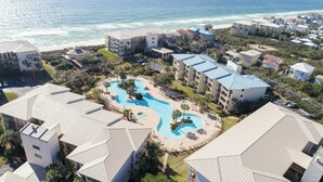 A resort with a large swimming pool, beachfront views, and multiple buildings with balconies.