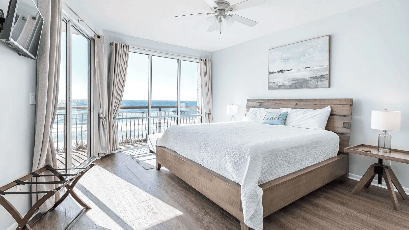 Ein Schlafzimmer mit einem großen Bett, Meerblick, Deckenventilator und einem Bild an der Wand.