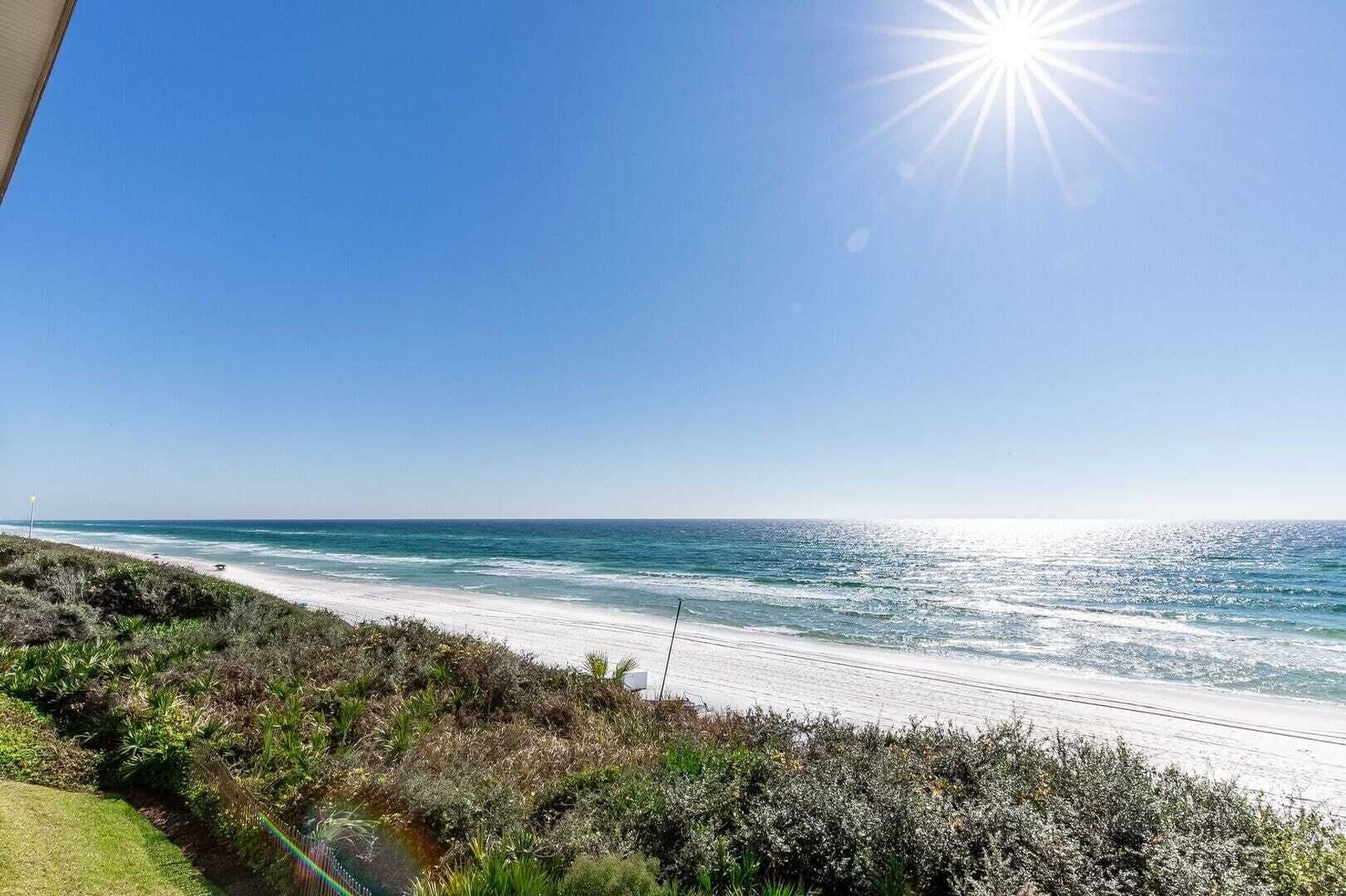 A coastal view with a clear sky, a sandy beach, and ocean waves.