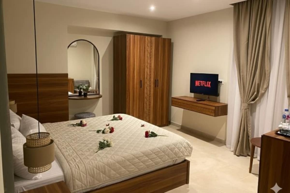 Une chambre d’hôtel avec un lit, une armoire en bois, une télévision et une table de chevet.