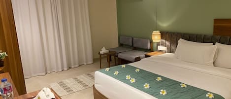 A hotel room with a bed, a desk, a chair, and a window with curtains.