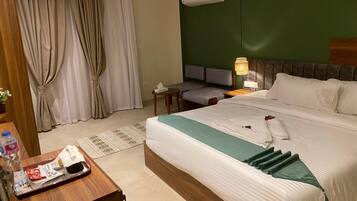 Una habitación de hotel con una cama, un escritorio, una silla, una lámpara y una ventana con cortinas.
