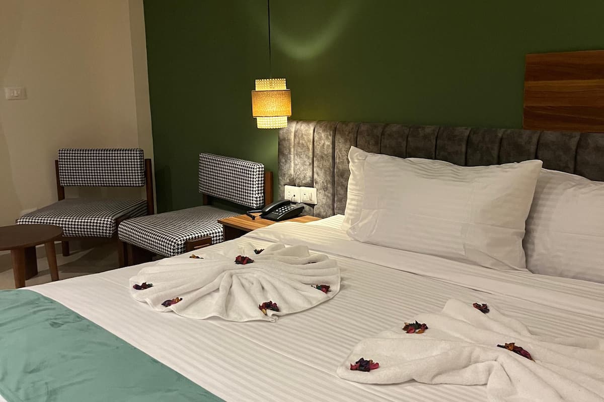 Ett hotellrum med en säng, ett skrivbord, en stol, en telefon och en luftkonditioneringsanläggning.