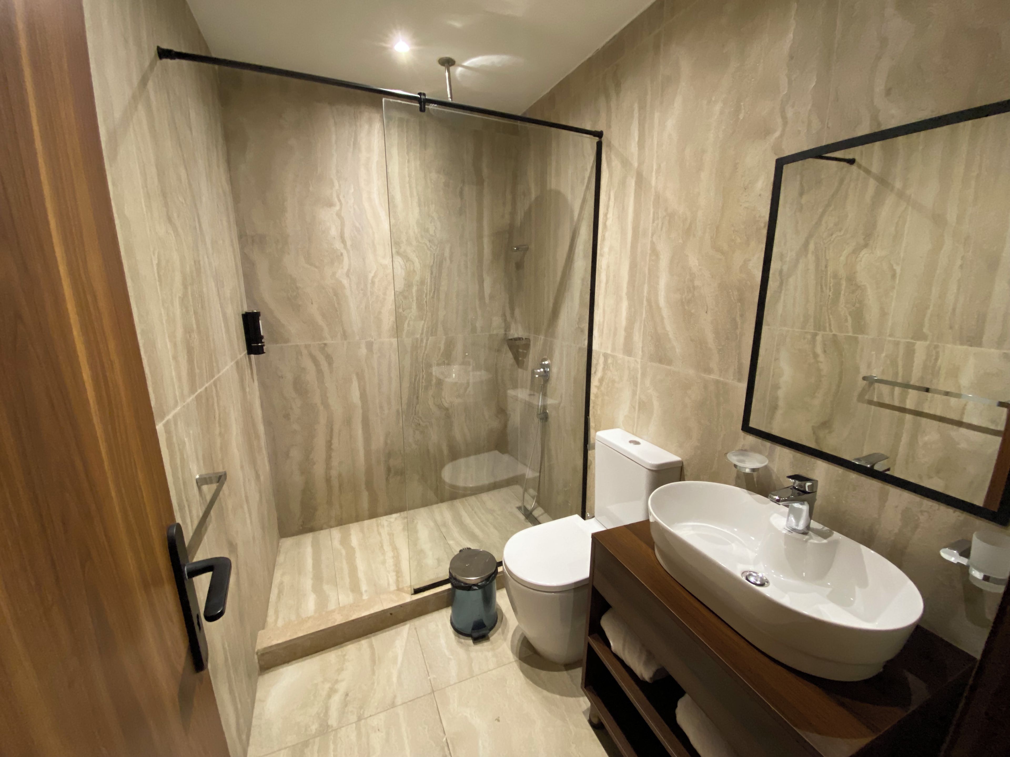 Ein modernes Badezimmer mit einer gläsernen Duschkabine, einer weißen Toilette und einem Waschtisch.
