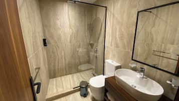 Ein modernes Badezimmer mit einer gläsernen Duschkabine, einer weißen Toilette und einem Waschtisch.