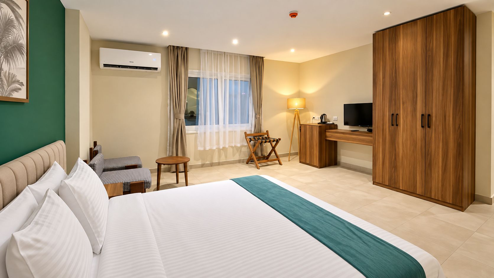 Habitación de hotel con cama, escritorio, televisor y armario.