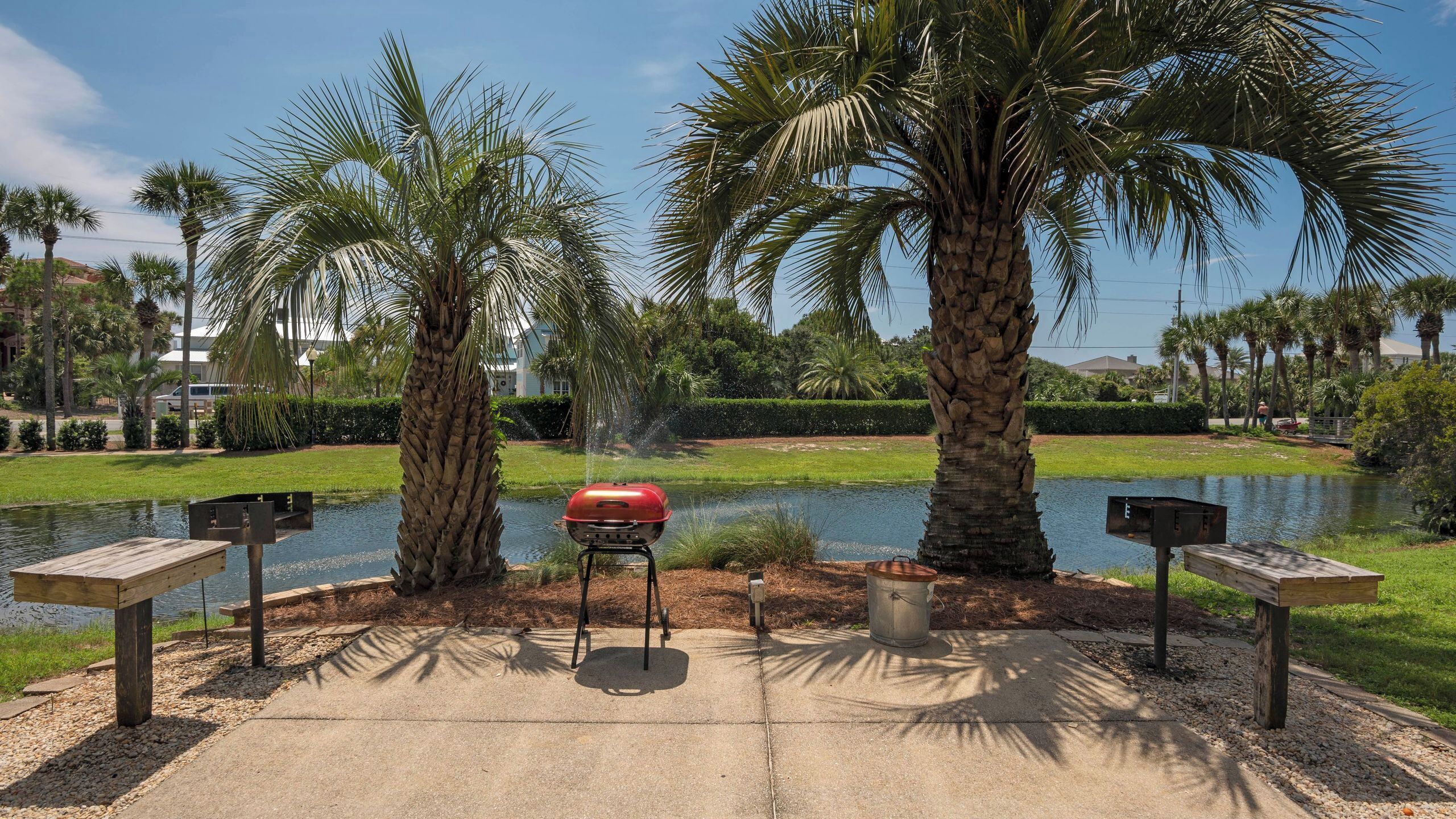 A patio with a grill, benches, and a pond.