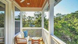 A covered porch with a wooden ceiling, white railings, and a view of a forested area. - Amour La Mer by Avantstay Rooftop Patio, Pool Access, Walk to Beach (Panama City Beach)