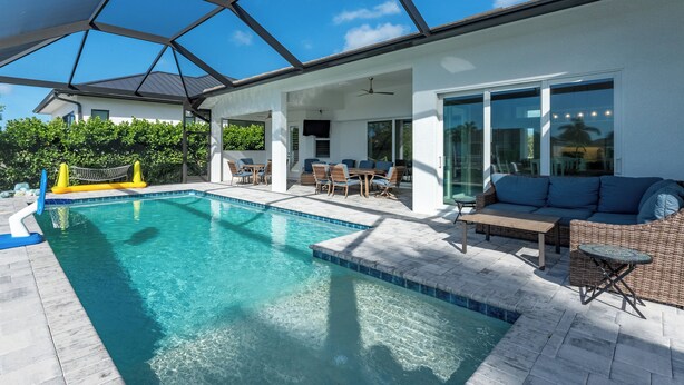Ein Pool mit Glasdach, eine Terrassenanlage mit Gartenmöbeln und Blick ins umgebende Grün.