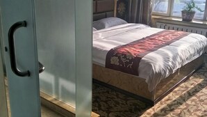 Quarto com uma cama, uma janela com uma planta e um radiador.