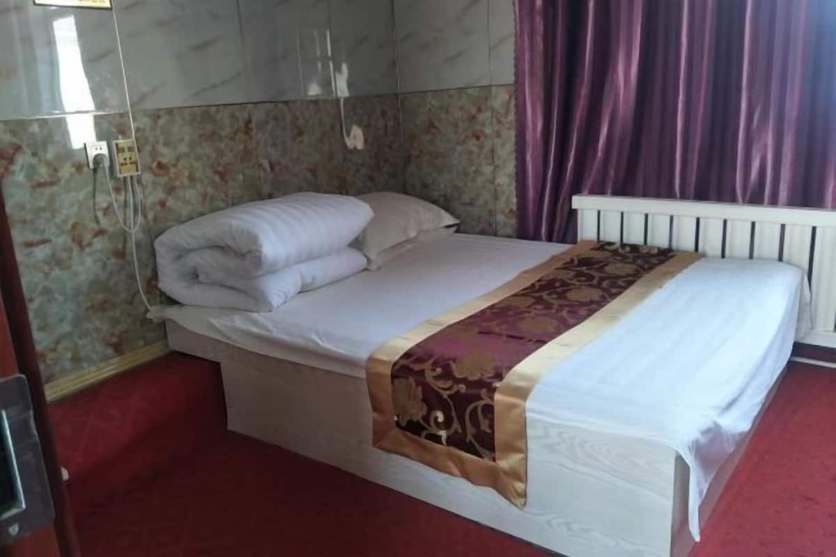 A single bed with a white headboard and footboard, a patterned throw blanket, and a floral wallpaper backdrop.