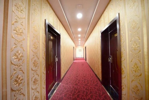 A hotel hallway with a red carpet, ornate wall designs, and doors on either side. - Shunhang Hotel (Harbin Taiping International Airport Branch) (Harbin)