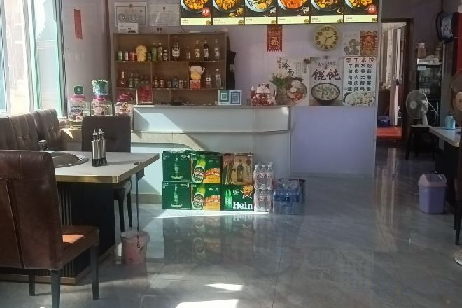 A restaurant interior with a counter, seating area, and various food items displayed.