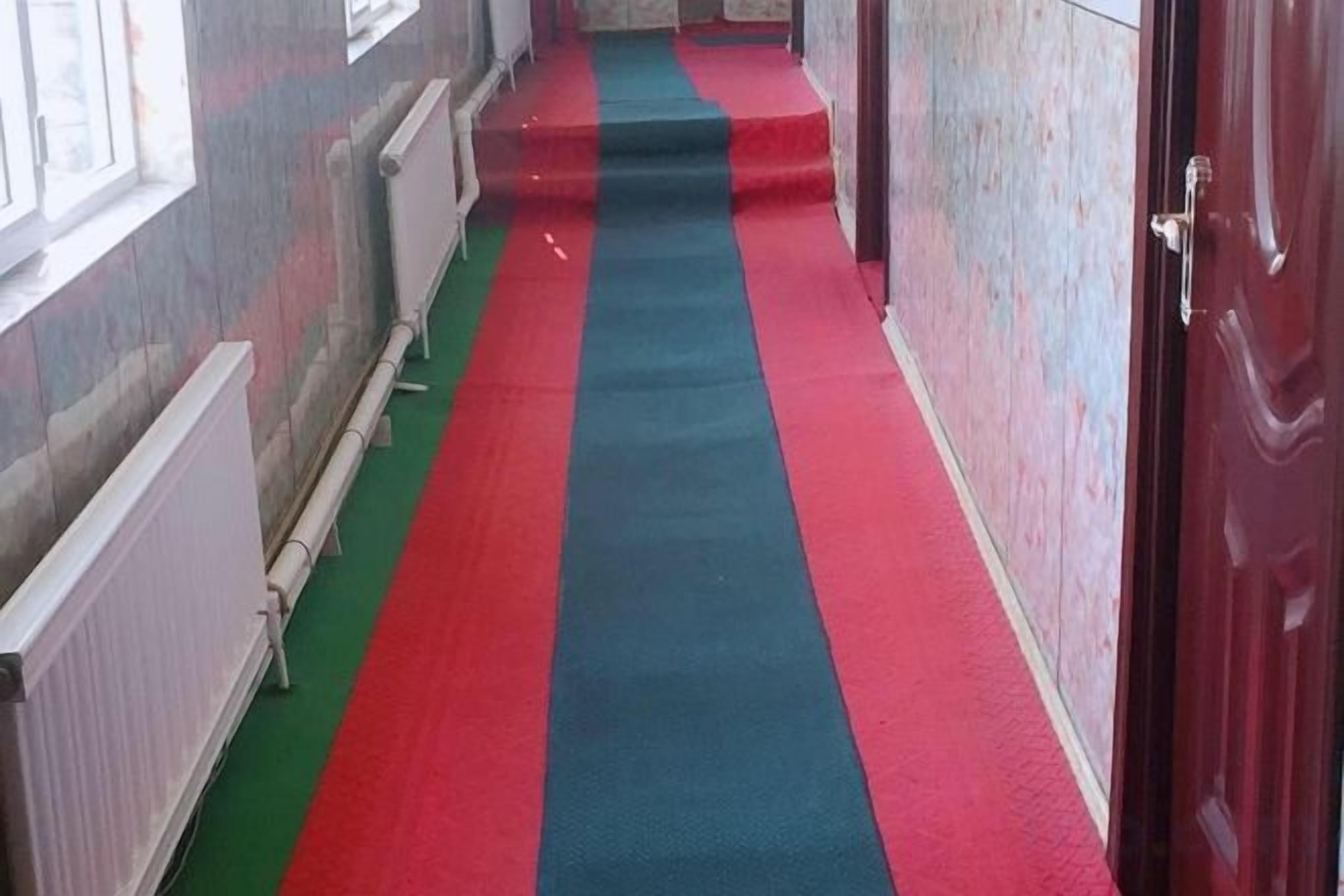 A corridor with a red carpet leading to a door.