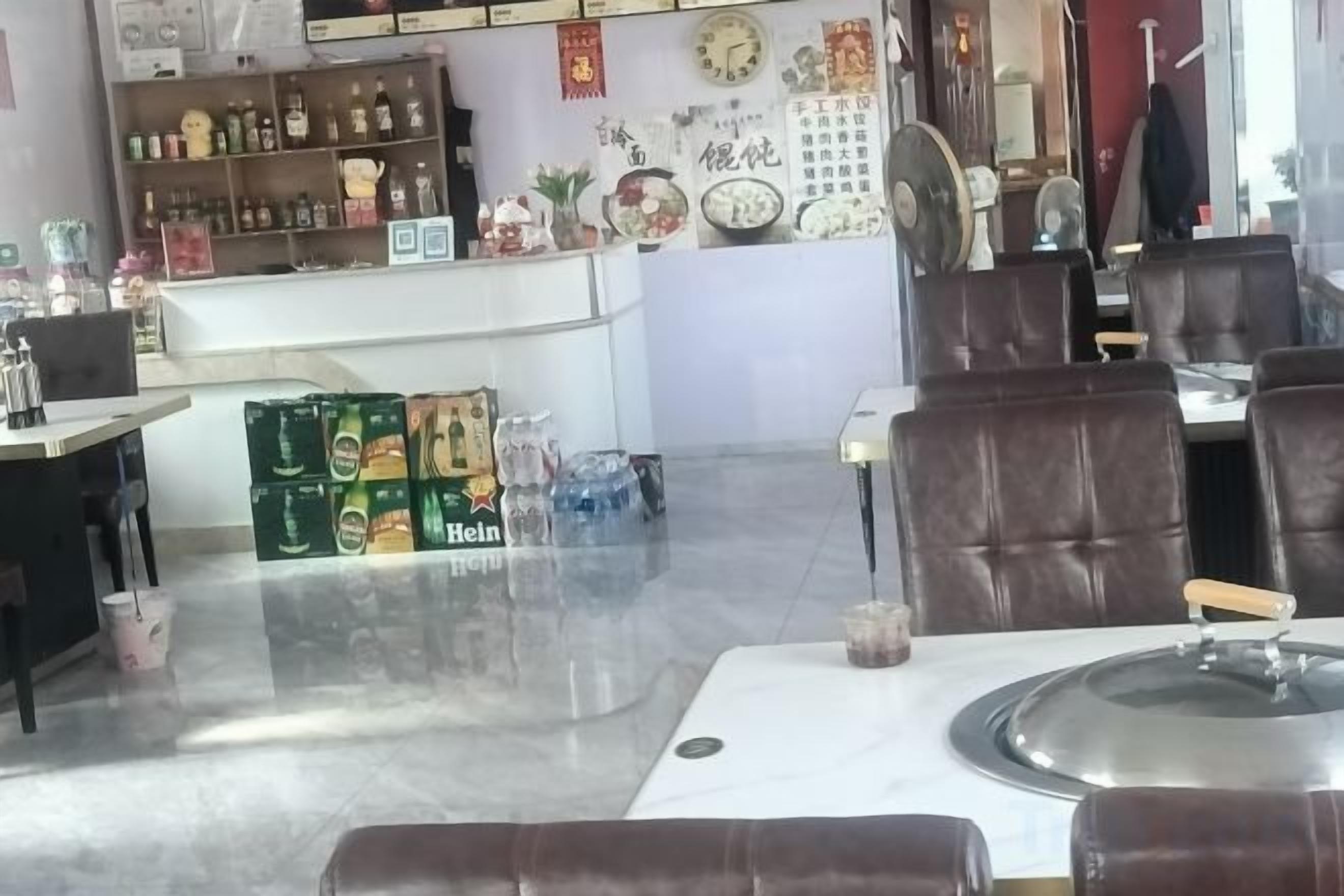 Interior de un restaurante con mesas, sillas, una barra con botellas y una pared decorada.