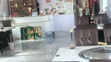 Interior de un restaurante con mesas, sillas, una barra con botellas y una pared decorada.