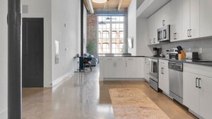 A spacious kitchen with modern appliances, a large window, and exposed wooden beams on the ceiling. - Modern Escape | Pool | Easy Access to DT & More! (Greenville)