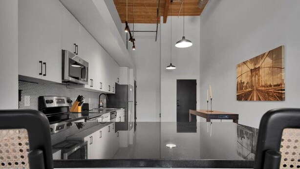 Una cocina moderna con una isla central, electrodomésticos de acero inoxidable e iluminación colgante.