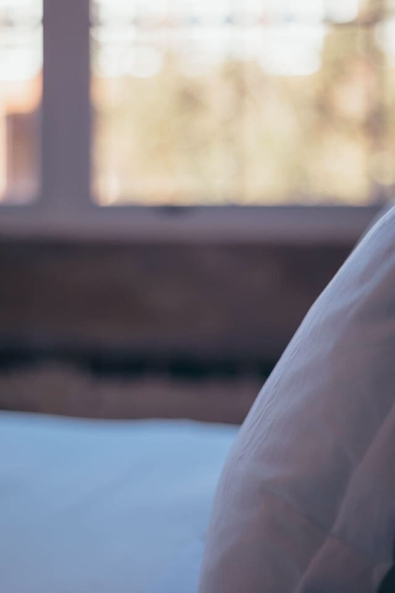 A blurred view of a room with a window, a bed, and a wooden floor.