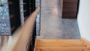 Una escalera de madera que conduce a una habitación con un armario oscuro y suelo de baldosas.