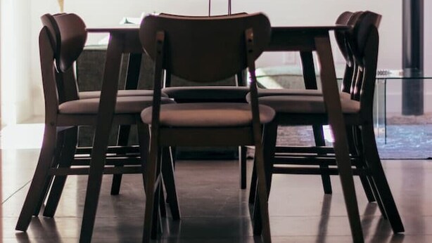 Un comedor con una mesa y cuatro sillas, un cuadro en la pared y una planta.