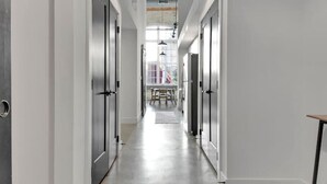A modern hallway with a polished concrete floor, white walls, and wooden ceiling beams.