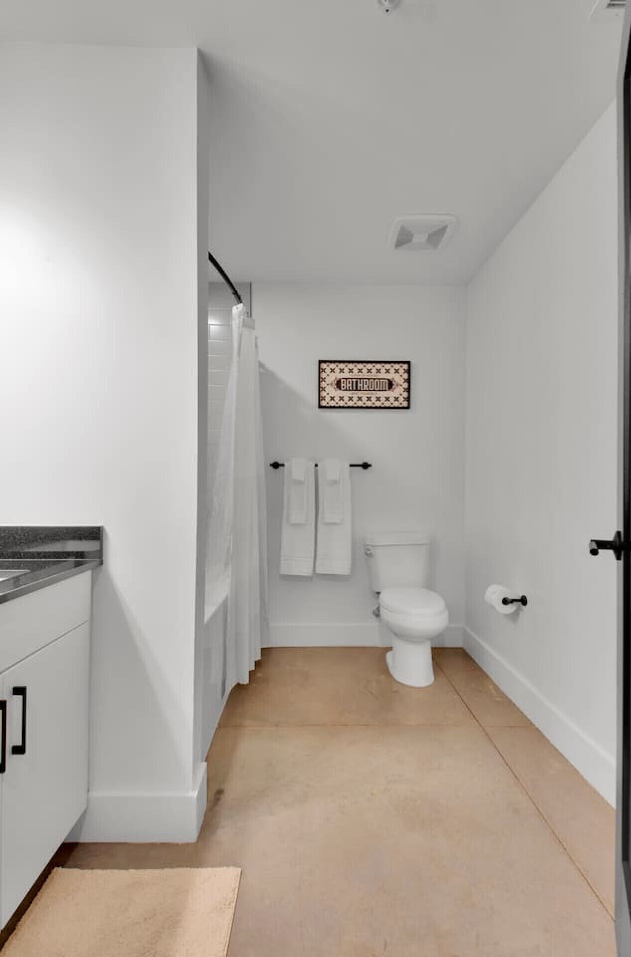 Une petite salle de bain comprenant des toilettes, un porte-serviettes et une pancarte indiquant « SALLE DE BAIN » sur le mur.