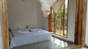 A bedroom with a bed, pillows, a mosquito net, and a window with a view of greenery. - Serene villa on Wasini island, mkwiro village pet friendly  (Kwale County)