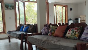A spacious room with a large bed, wooden beams on the ceiling, and large windows offering a view of greenery outside. - Serene villa on Wasini island, mkwiro village pet friendly  (Kwale County)