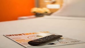 A remote control on a bed with a magazine and a pillow. - Sovotel Boutique Hotel @ Puchong (Puchong)