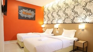 A hotel room with two beds, a headboard with a floral pattern, a wall-mounted welcome sign, and bedside lamps. - Sovotel Boutique Hotel @ Puchong (Puchong)
