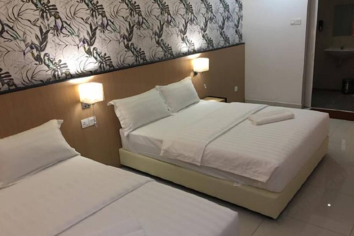 A hotel room with two beds, a floral wall design, and bedside lamps.
