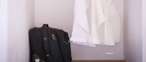 A closet with a hanging rod and a suitcase.