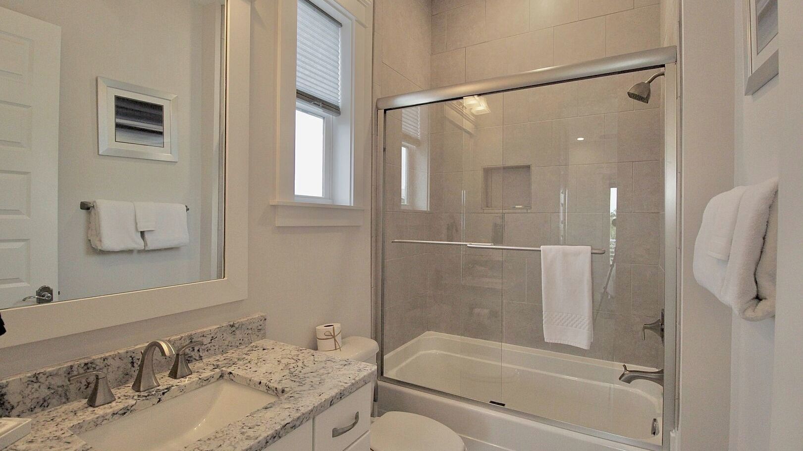 Une salle de bain avec une douche à parois de verre, un lavabo doté d’un plan de toilette en marbre et des toilettes.