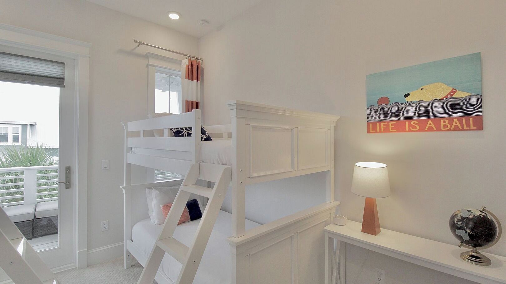 A bedroom with a bunk bed, a bedside table with a lamp, a globe, and a motivational poster.