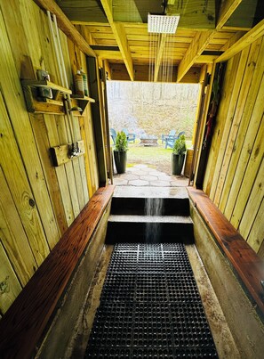 Una sauna de madera con un banco, un cabezal de ducha y vistas al exterior.