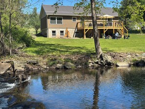 A house with a deck and a pond in front.