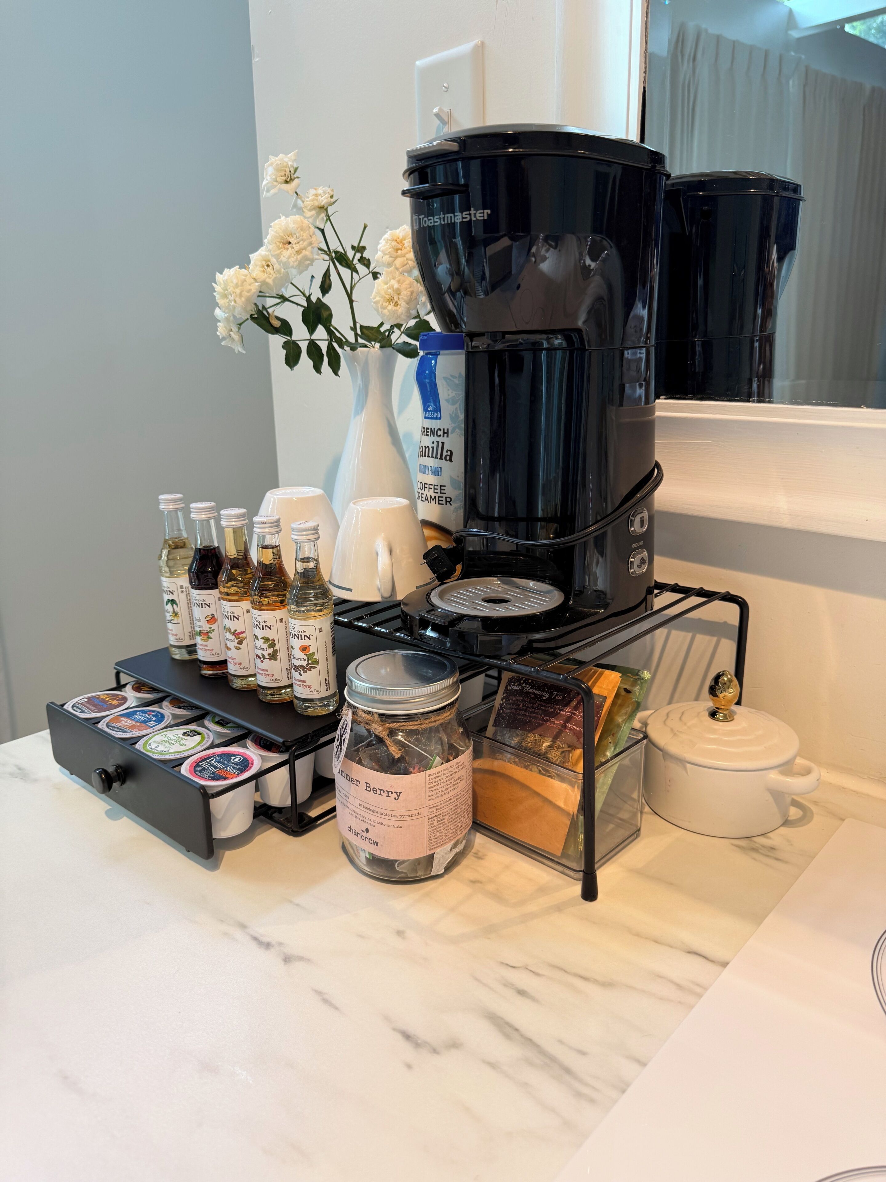 Eine Küchenarbeitsplatte mit einer Kaffeemaschine, einem Marmeladenglas und verschiedenen Gewürzen.