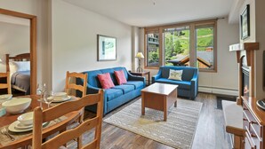 A spacious living room with a blue sofa, wooden coffee table, and a dining area with a wooden table and chairs.