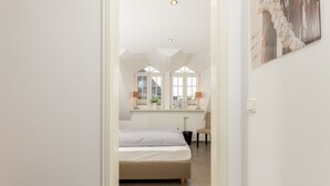 Een slaapkamer met een bed, een stoel, een bureau en een raam met uitzicht.