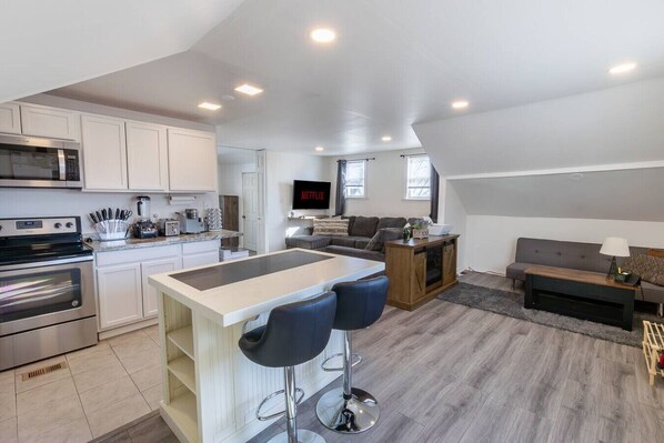 A modern kitchen with a built-in microwave, stove, and bar stools.